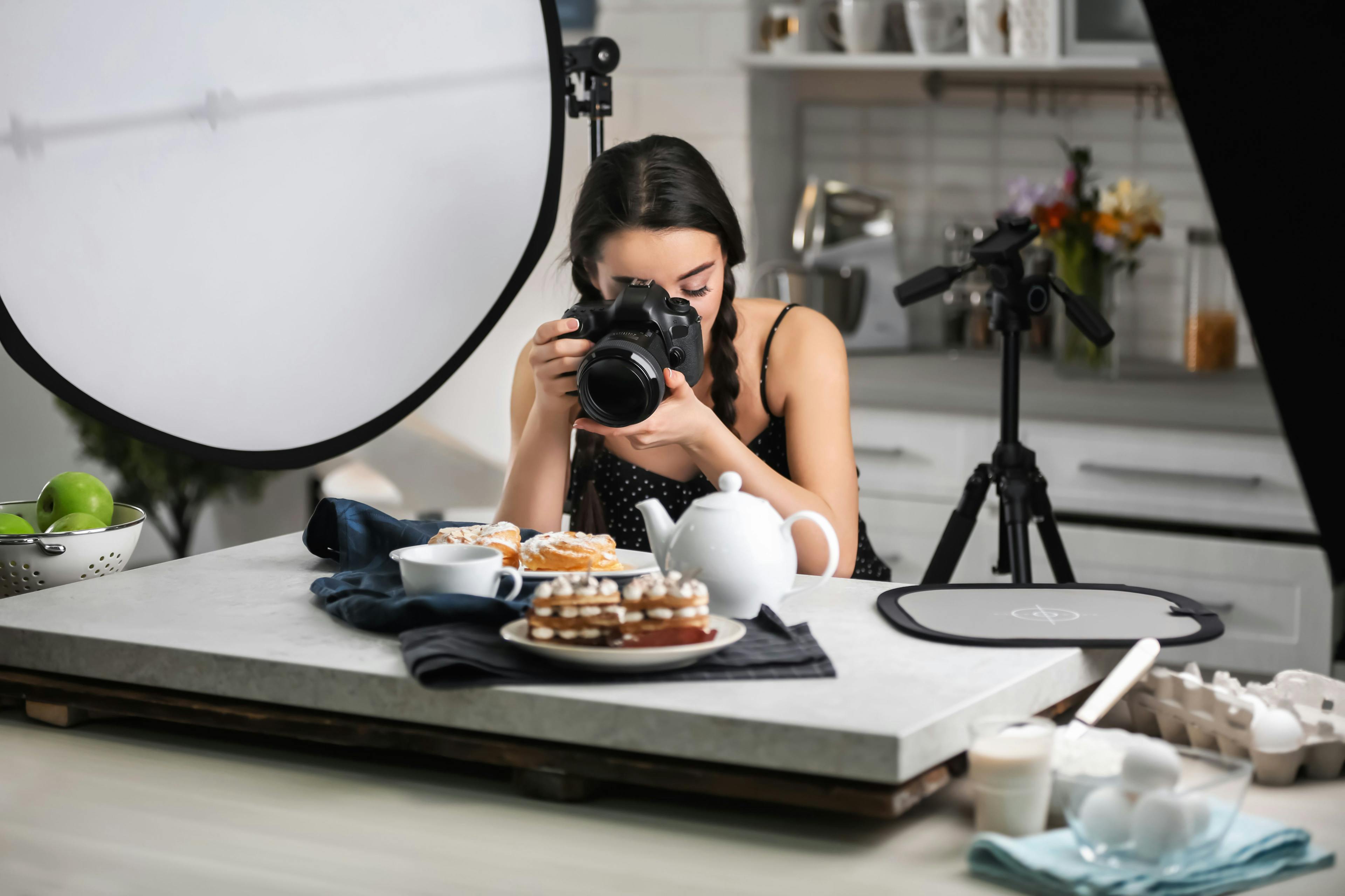 Food photography for digital menus: Woman capturing table spread.